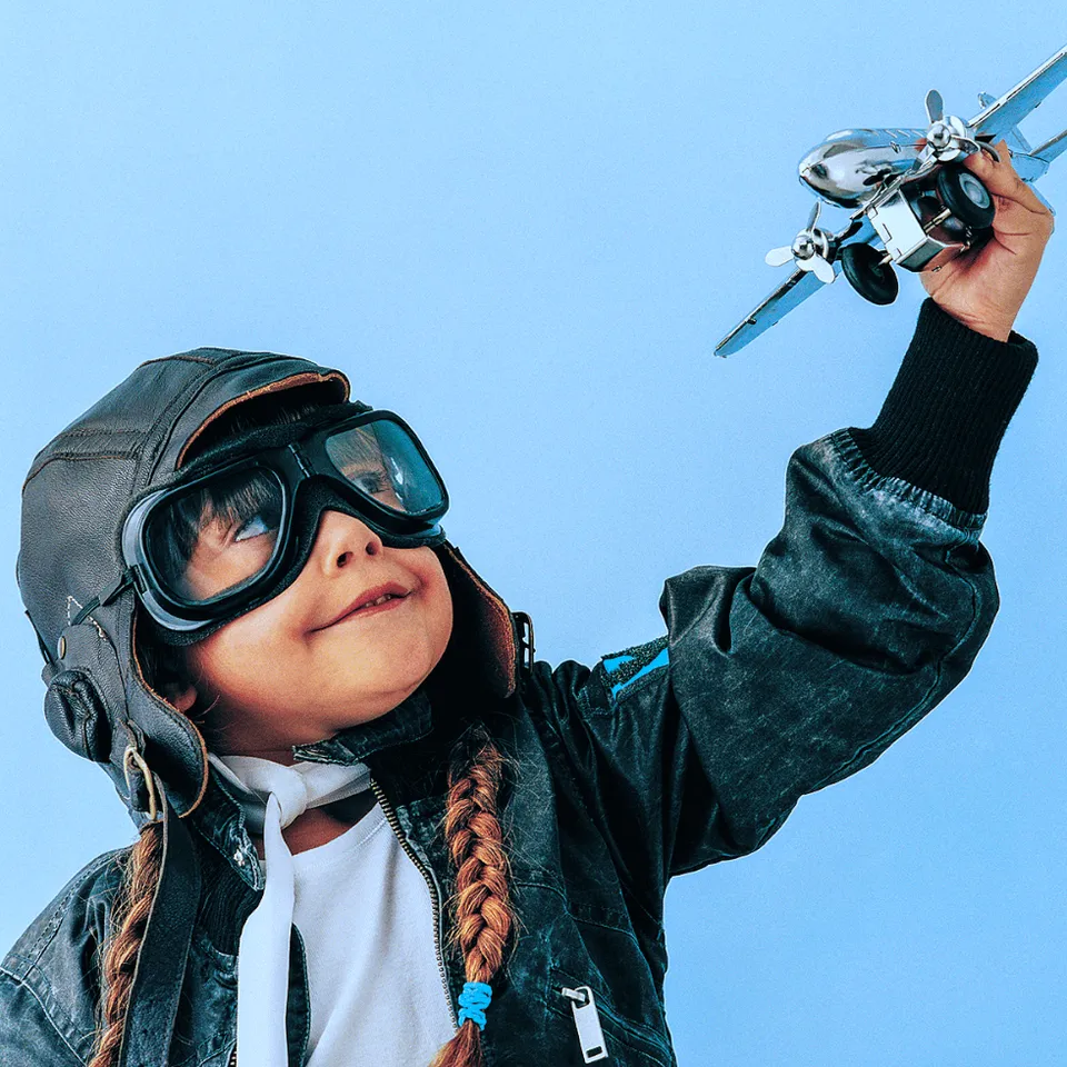 little-girl-wearing-aviator-goggles-pilot-hat-playing-with-model-plane